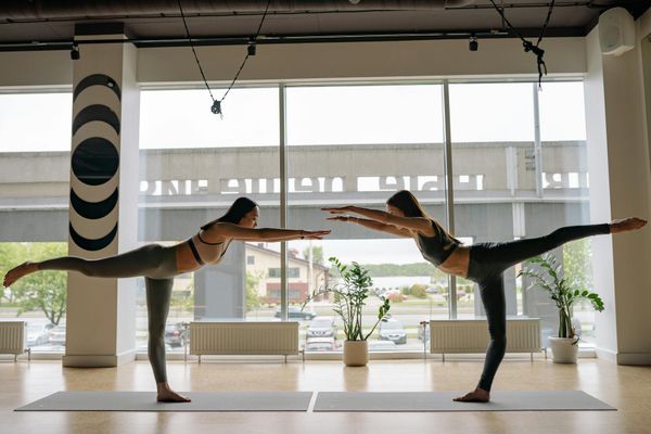Woman transitioning smoothly between two yoga poses in a well-lit studio.